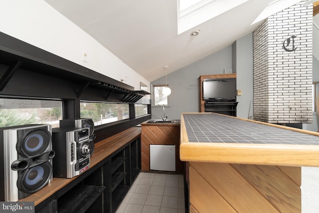 bar with lofted ceiling with skylight, sink, and light tile patterned floors