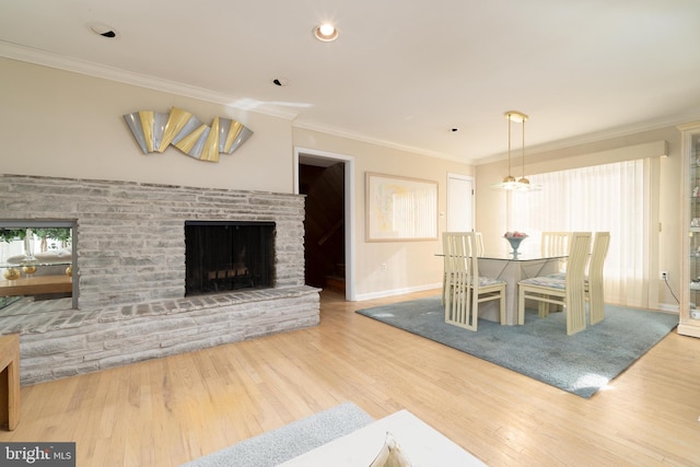 dining area with hardwood / wood-style flooring, crown molding, and a fireplace