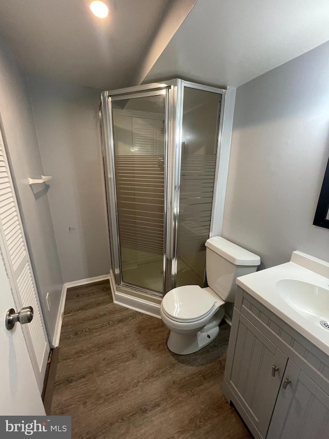 bathroom with vanity, toilet, a shower with door, and hardwood / wood-style floors