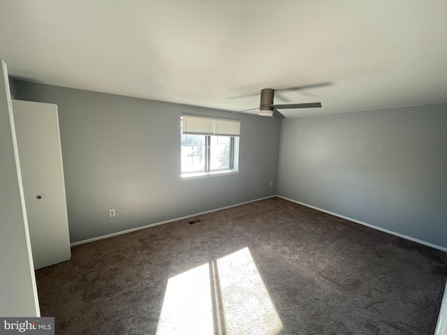 empty room with ceiling fan and dark carpet