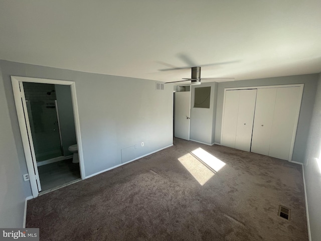 unfurnished bedroom with a closet, carpet floors, ceiling fan, and ensuite bath