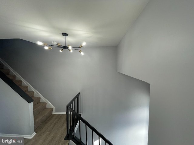 staircase featuring an inviting chandelier and hardwood / wood-style floors