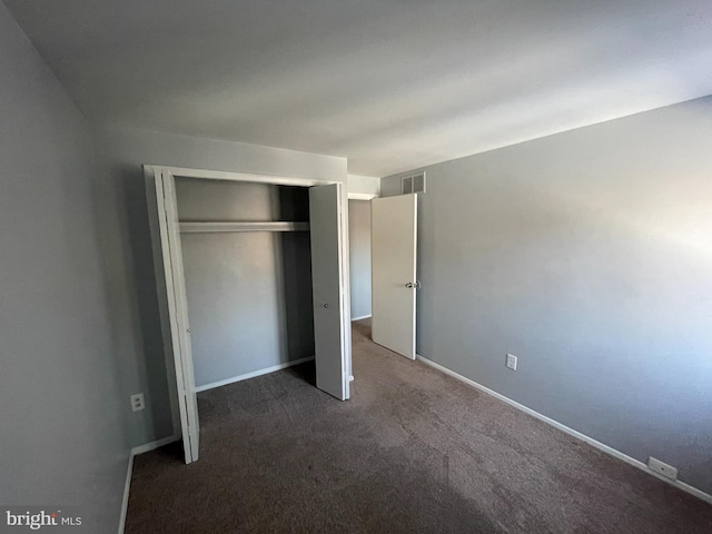 unfurnished bedroom featuring a closet and dark colored carpet