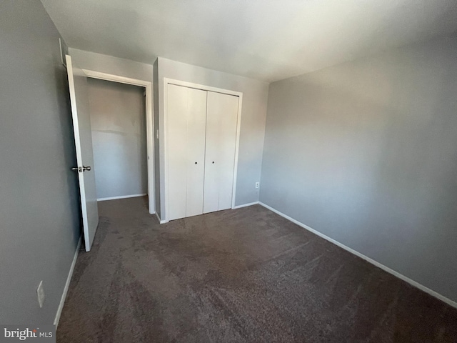 unfurnished bedroom with dark carpet and a closet