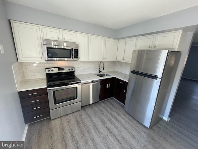 kitchen featuring appliances with stainless steel finishes, sink, decorative backsplash, dark brown cabinets, and light wood-type flooring