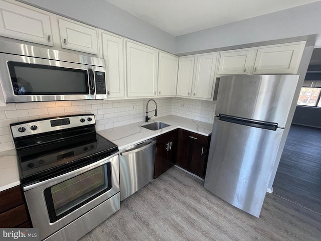 kitchen with dark brown cabinetry, sink, light hardwood / wood-style flooring, and stainless steel appliances