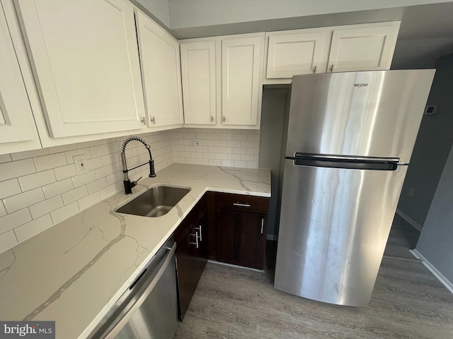 kitchen with sink, decorative backsplash, dark brown cabinetry, stainless steel appliances, and light stone countertops