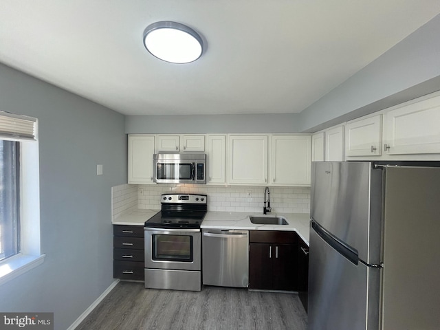 kitchen with sink, backsplash, stainless steel appliances, light hardwood / wood-style floors, and white cabinets