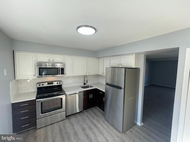 kitchen featuring sink, backsplash, stainless steel appliances, and white cabinets