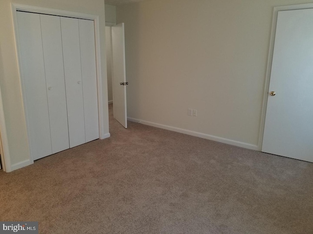 unfurnished bedroom featuring carpet floors, a closet, and baseboards