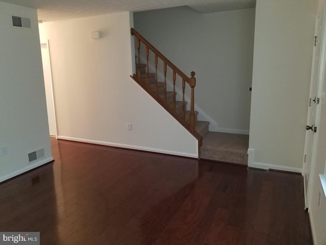 interior space with stairs, visible vents, baseboards, and wood finished floors