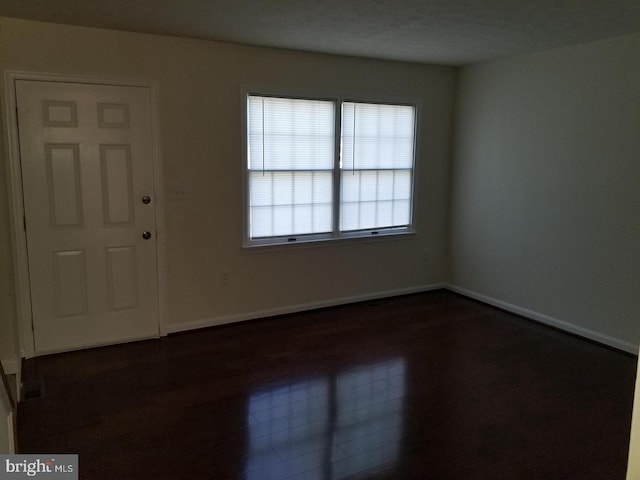 spare room featuring dark wood finished floors and baseboards