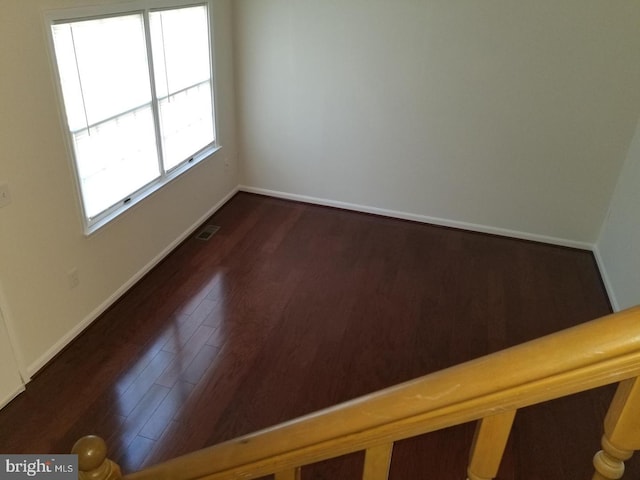 unfurnished room featuring wood finished floors, visible vents, and baseboards