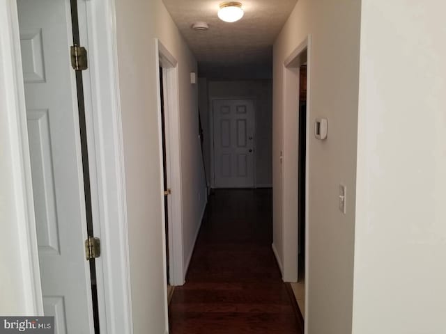 hallway with a textured ceiling and dark wood-style floors