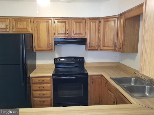 kitchen with under cabinet range hood, a sink, light countertops, black appliances, and brown cabinetry