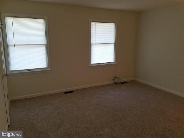 spare room featuring baseboards, visible vents, and carpet flooring