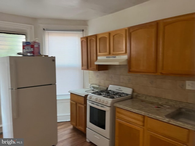 kitchen featuring white gas range, refrigerator, backsplash, wood-type flooring, and sink