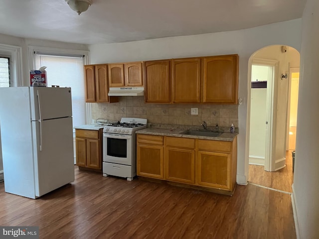 kitchen with white appliances, tasteful backsplash, hardwood / wood-style floors, and sink