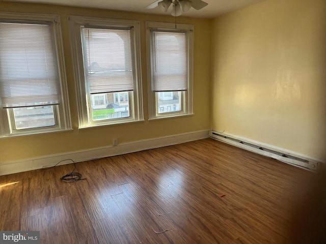 spare room featuring a baseboard heating unit, ceiling fan, and hardwood / wood-style floors