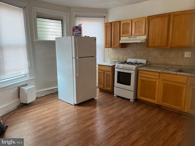 kitchen featuring white appliances, light hardwood / wood-style floors, backsplash, and sink