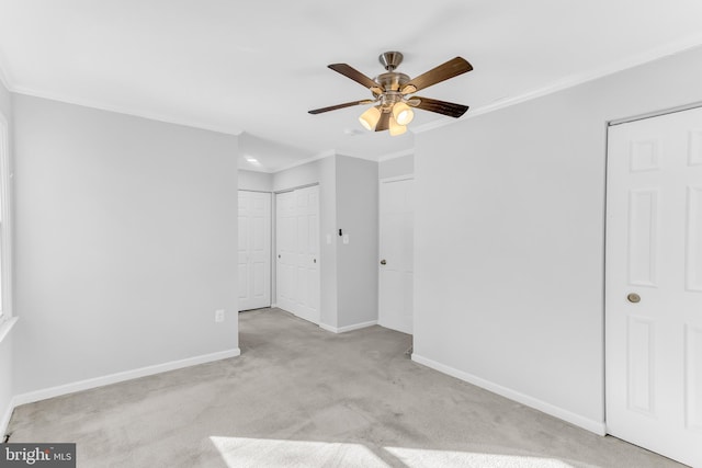 empty room with ceiling fan, light colored carpet, and crown molding