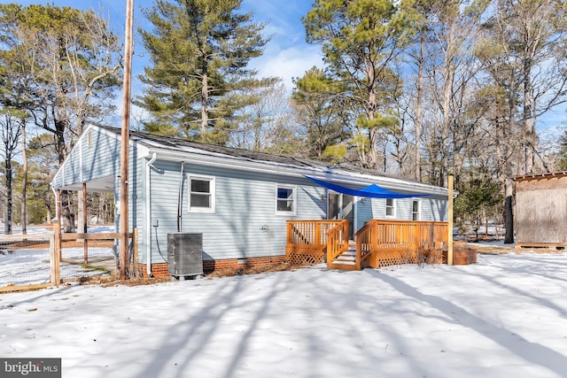 snow covered house featuring a wooden deck and central AC