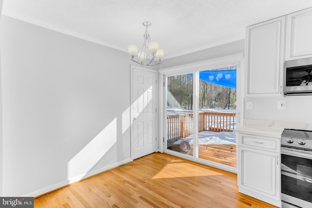 unfurnished dining area featuring light wood-type flooring, ornamental molding, and an inviting chandelier