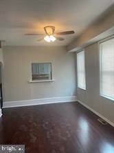 unfurnished living room with dark hardwood / wood-style floors, ceiling fan, and a healthy amount of sunlight