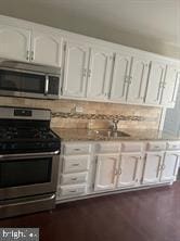 kitchen with white cabinets, backsplash, and stainless steel appliances