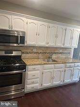 kitchen with decorative backsplash, appliances with stainless steel finishes, white cabinetry, and sink