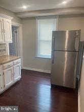 kitchen featuring white cabinets, decorative backsplash, dark hardwood / wood-style flooring, and stainless steel refrigerator