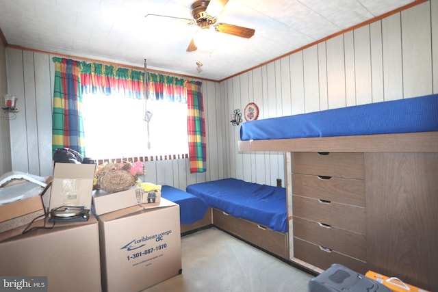 carpeted bedroom featuring crown molding, wood walls, ceiling fan, and radiator