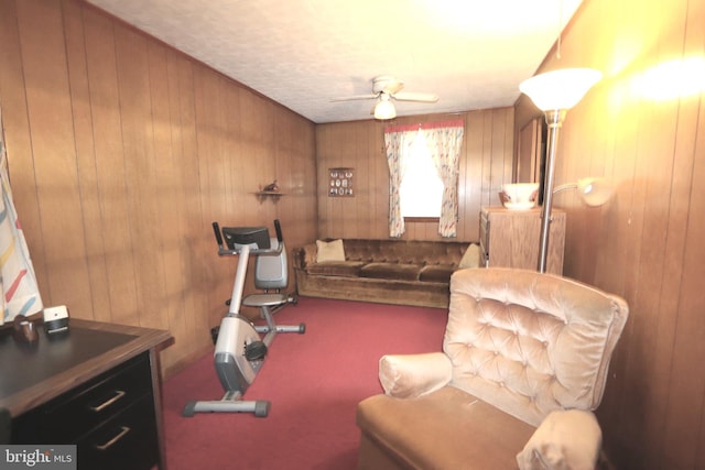 living room with ceiling fan, wooden walls, and a textured ceiling