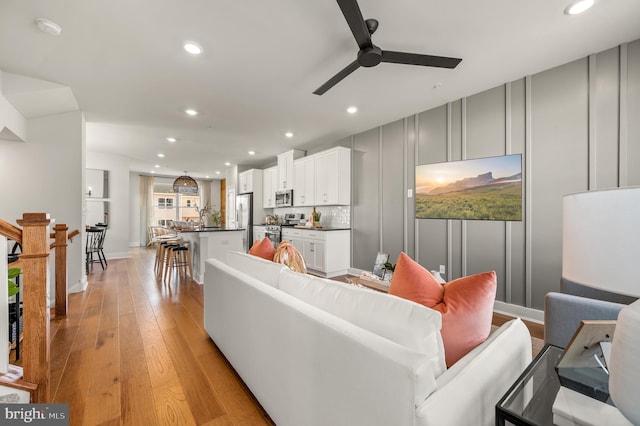 living room with ceiling fan and light hardwood / wood-style flooring