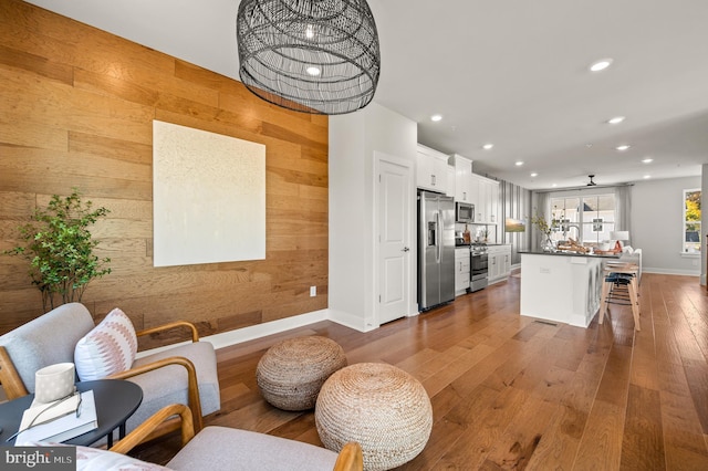 kitchen with white cabinets, stainless steel appliances, wooden walls, and a breakfast bar area