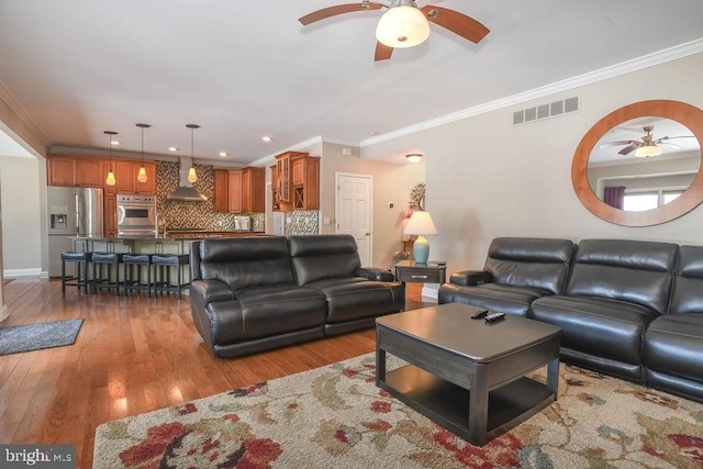 living room with hardwood / wood-style flooring, ceiling fan, and ornamental molding