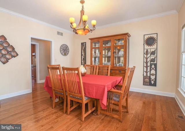 dining space featuring a chandelier, ornamental molding, and wood-type flooring