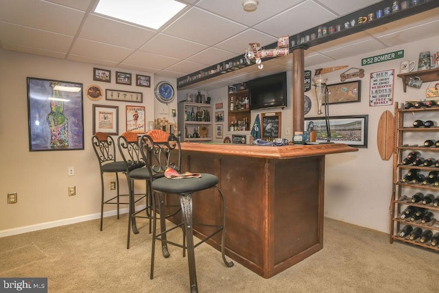 bar with a paneled ceiling and light carpet