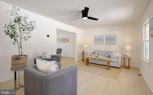 living room featuring light wood-type flooring, ceiling fan, and a healthy amount of sunlight