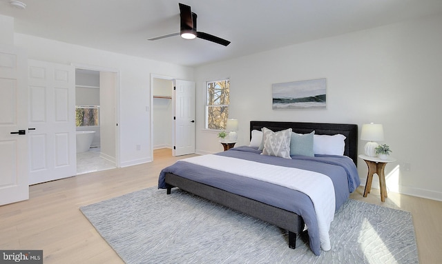 bedroom featuring ceiling fan, a walk in closet, ensuite bath, and light hardwood / wood-style flooring