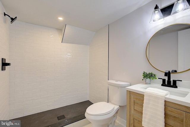 bathroom with toilet, a tile shower, and vanity