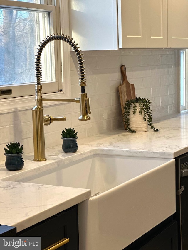 room details featuring decorative backsplash, light stone countertops, and white cabinetry