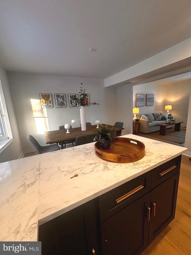 kitchen with light stone countertops, dark brown cabinets, and light hardwood / wood-style floors