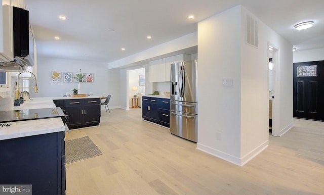 kitchen with light wood-type flooring, white cabinets, and stainless steel refrigerator with ice dispenser