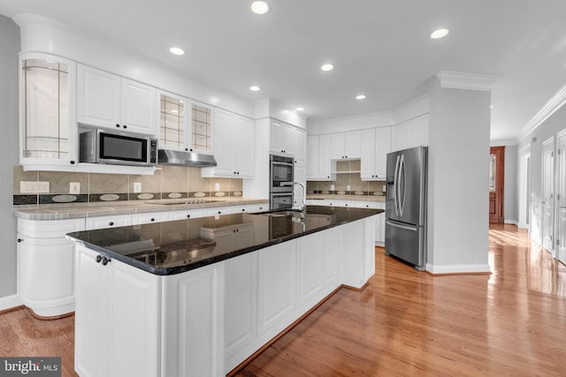 kitchen featuring light hardwood / wood-style floors, a center island with sink, appliances with stainless steel finishes, crown molding, and white cabinets