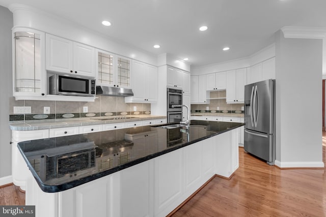 kitchen with white cabinets, appliances with stainless steel finishes, light hardwood / wood-style flooring, and a kitchen island with sink