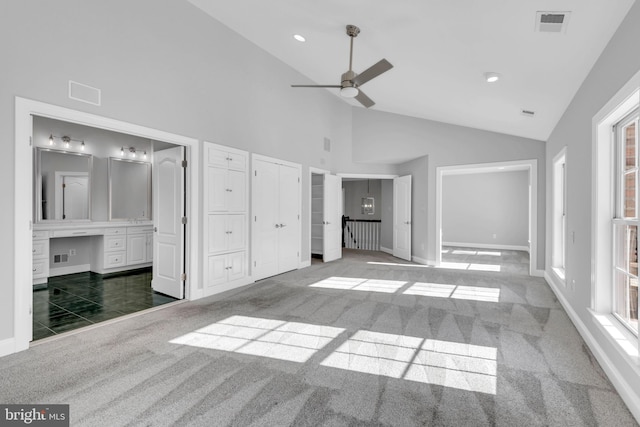 unfurnished bedroom featuring ensuite bath, ceiling fan, carpet floors, and high vaulted ceiling