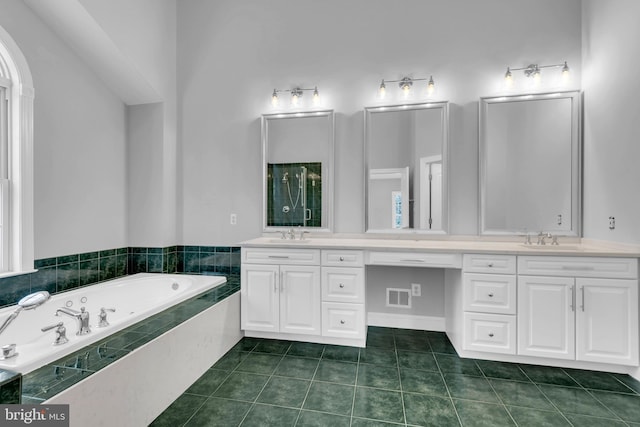 bathroom featuring vanity, tile patterned flooring, and tiled tub