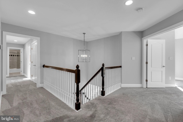 hall featuring light colored carpet and an inviting chandelier