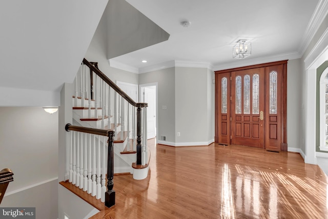 entrance foyer featuring a notable chandelier, crown molding, and light hardwood / wood-style flooring